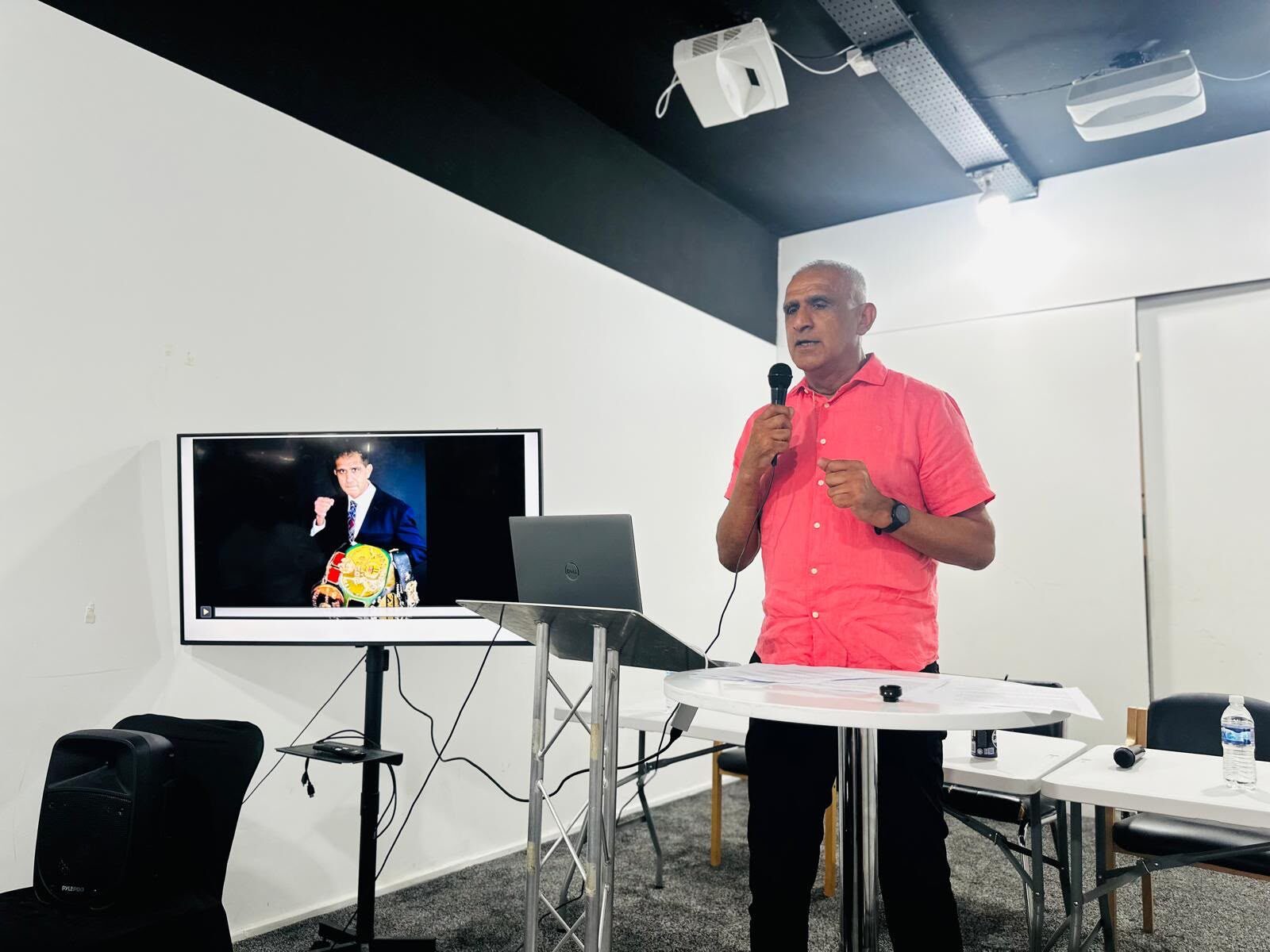 Kash speaking with belt on screen
